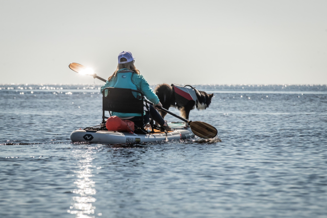 Vibe Cubera 125 being paddled on the water with a dog on board